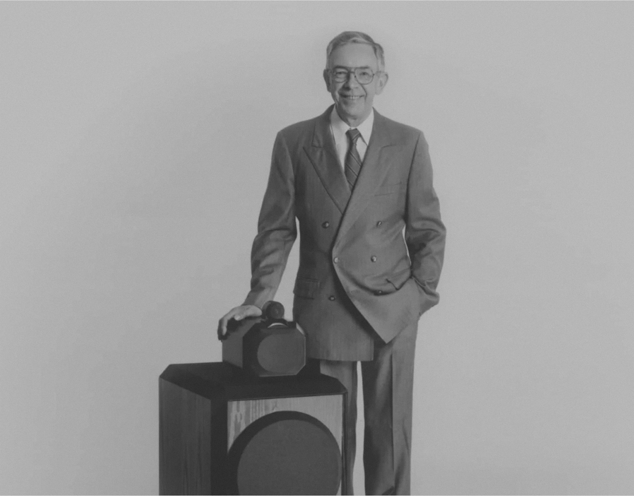 Bowers &amp;amp; Wilkins founder John Bowers in a black and white photo, posing with the original B&amp;amp;W 801 speaker.