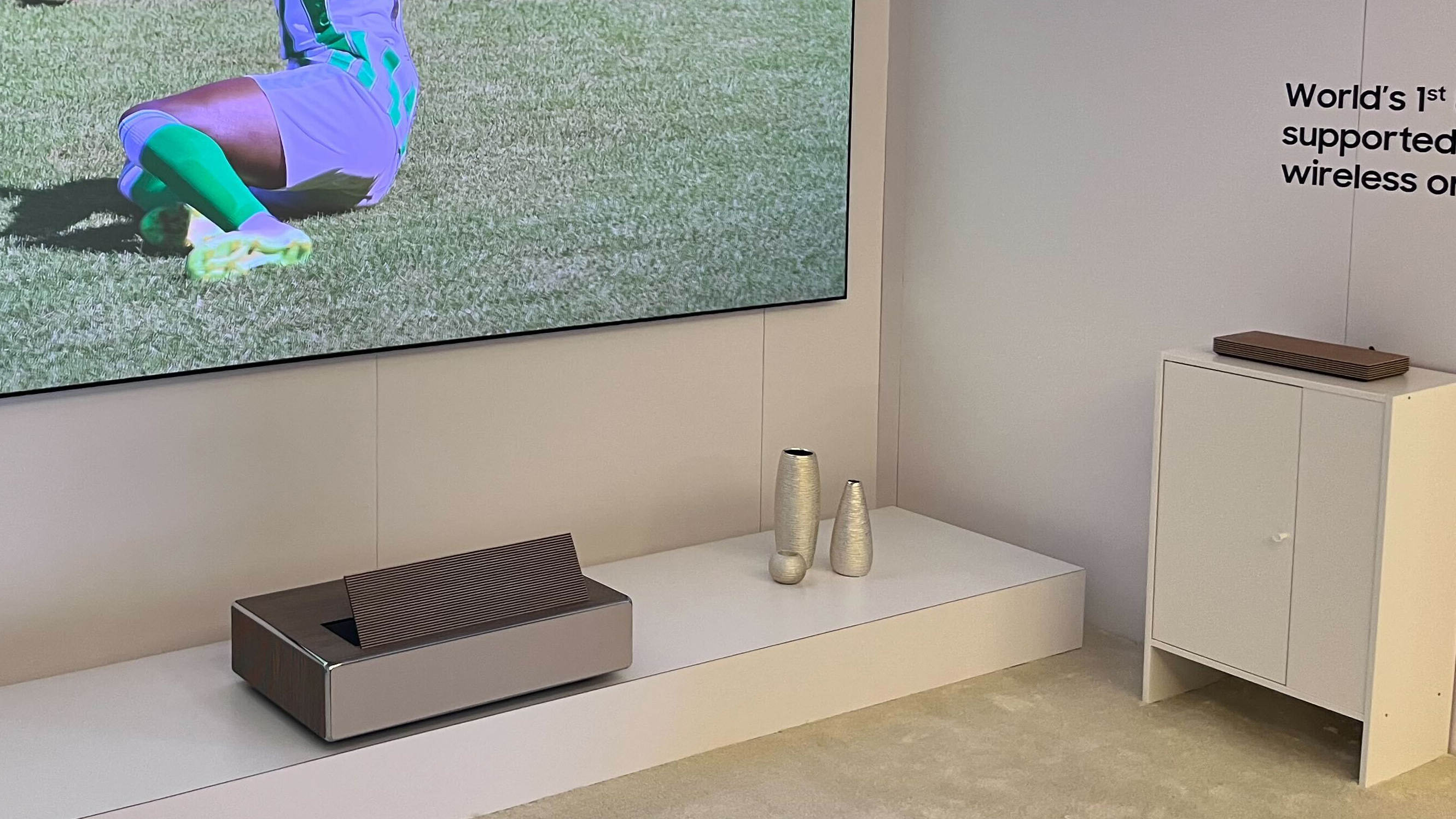 Samsung The Premiere 8K projecting a football match, with its wireless connection box on a separate unit