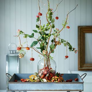 foragers arrangement with branches and glass vase with berries and nuts