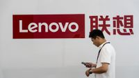 a person walking past a Lenovo signboard