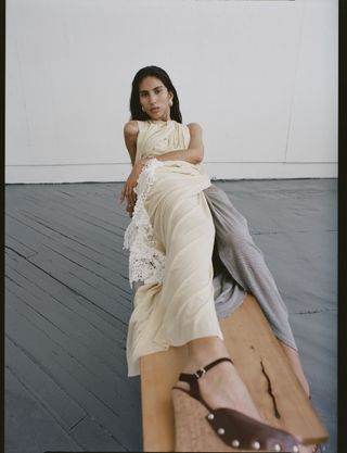 a model wears a butter yellow draped dress with lace detailing with cork wedge sandals