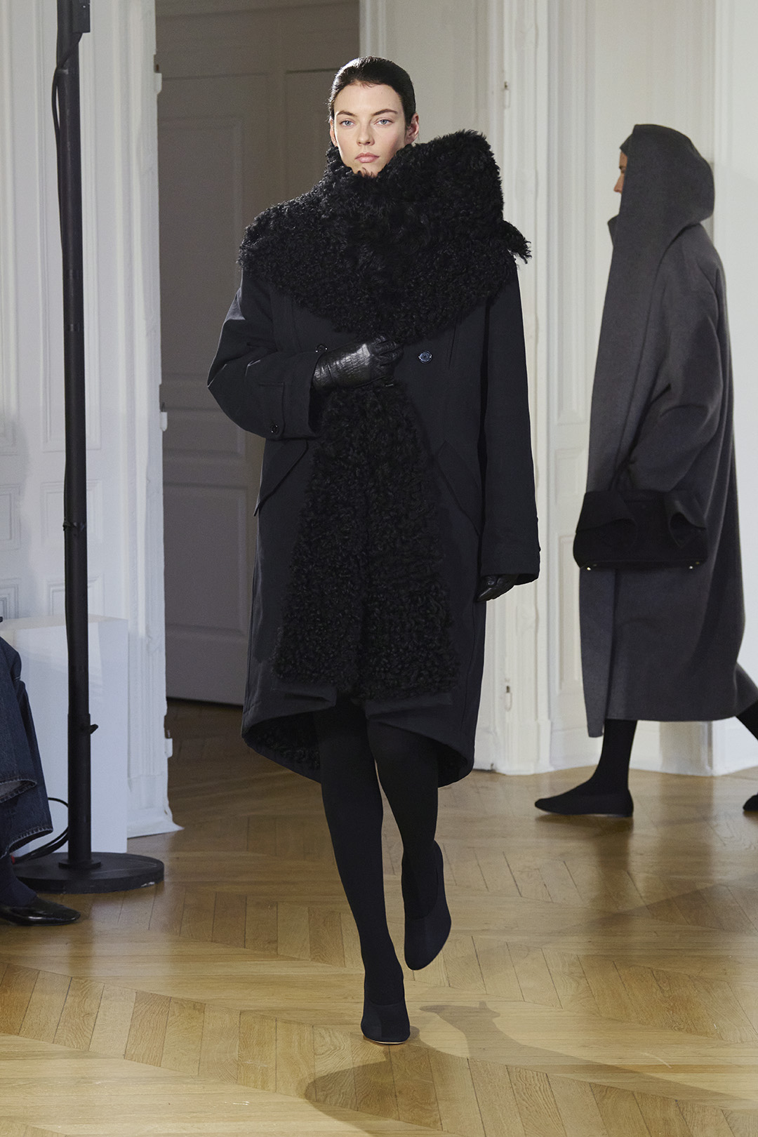 a model at Toteme Fall 2026 wearing a black coat, large fur scarf, and black leggings