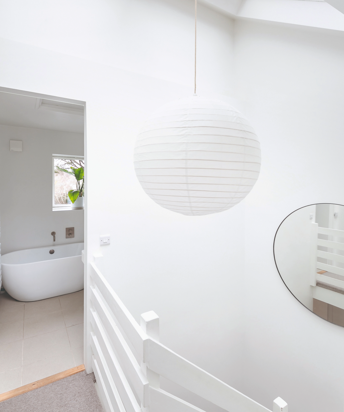 View from the top of the staircase with a pendant light shade hanging and a glimpse into the bathroom
