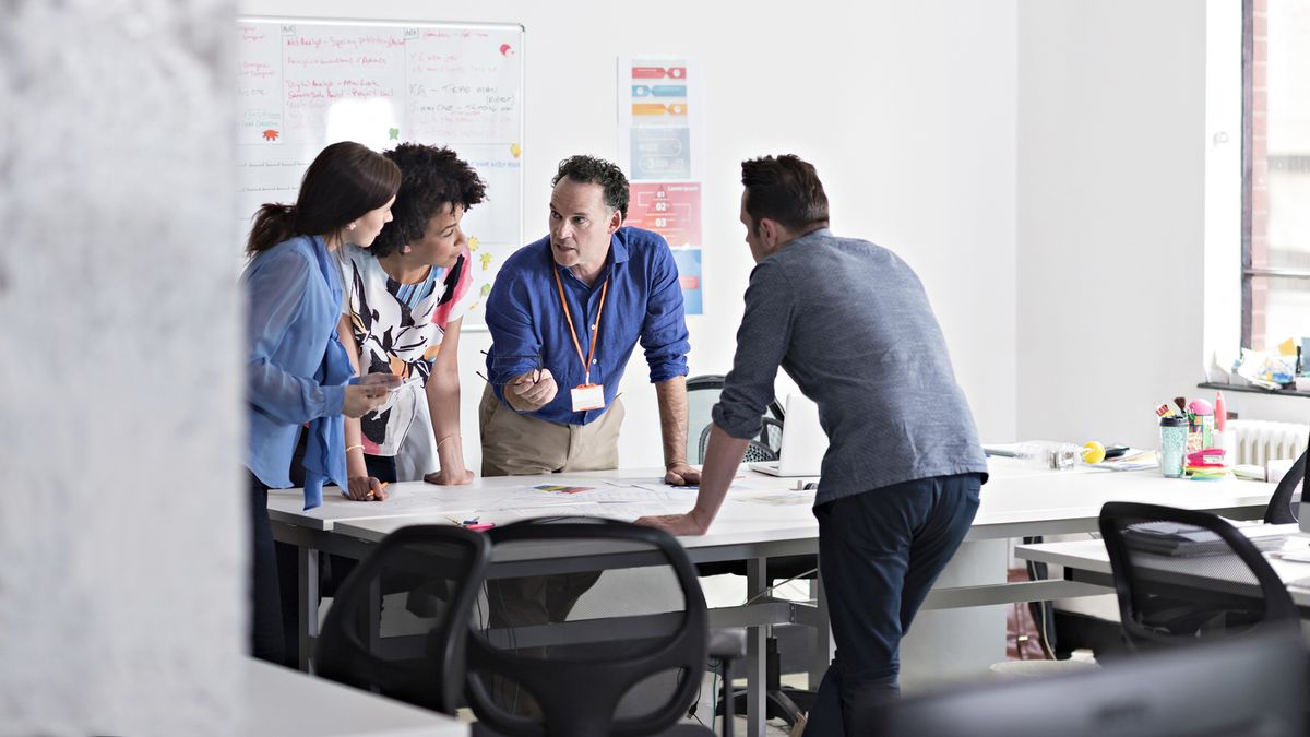 A group of four colleagues standing round a table strategizing