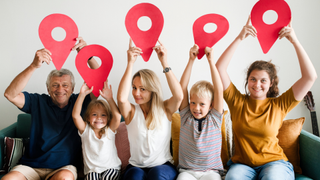 A family on a couch holding 'location' style pins above their head