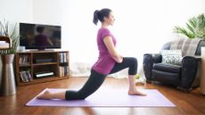 woman does a kneeling hip flexor stretch on yoga mat