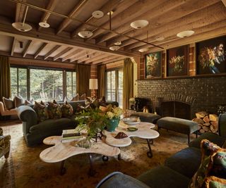 A large chalet living room with three large sofas, a custom coffee table, a large brick fireplace and custom light fixtures on the ceiling