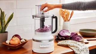 KitchenAid food processor in a kitchen chopping vegetables