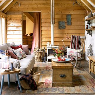 A barn conversion living room with timber cladding, a grey sofa, wooden table and a log burner