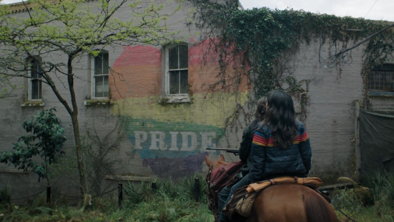 Bella Ramsey as Ellie and Isabela Merced as Dina in front of Pride sign on The Last of Us Season 2.