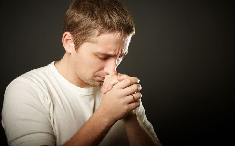 guy prays with his hands folded in front of him