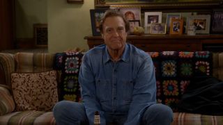 John Goodman as Dan Conner saying goodnight to the camera and sitting on a couch on The Conners.
