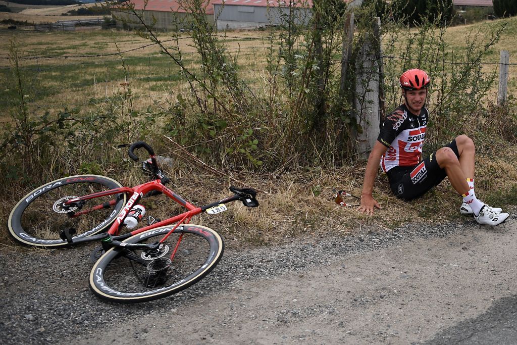 Team Lotto rider Belgiums Brent Van Moer R sits on the grass after falling during the first stage of the 72nd edition of the Criterium du Dauphine cycling race 2185 km between ClermontFerrand and SaintChristoenJarez on August 12 2020 Photo by AnneChristine POUJOULAT AFP Photo by ANNECHRISTINE POUJOULATAFP via Getty Images