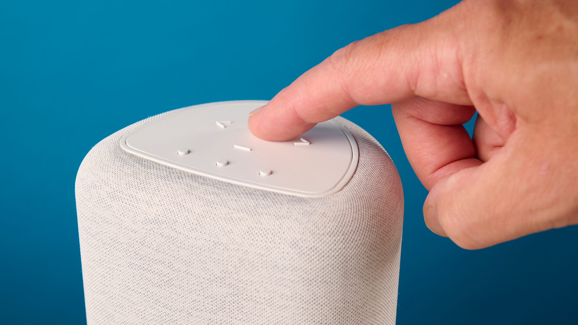 the bluesound pulse flex wi-fi speaker in pale gray photographed against the blue tom's guide background