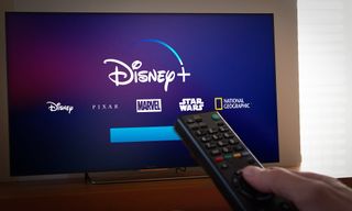 Image de Disney Plus affiché sur un téléviseur avec une main tenant une télécommande