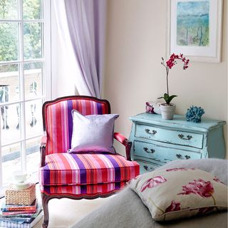 guest bedroom with arm chair and cushions and drawer