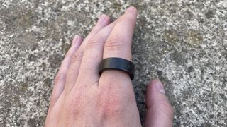 The UltraHuman Ring Air on someone's hand over concrete