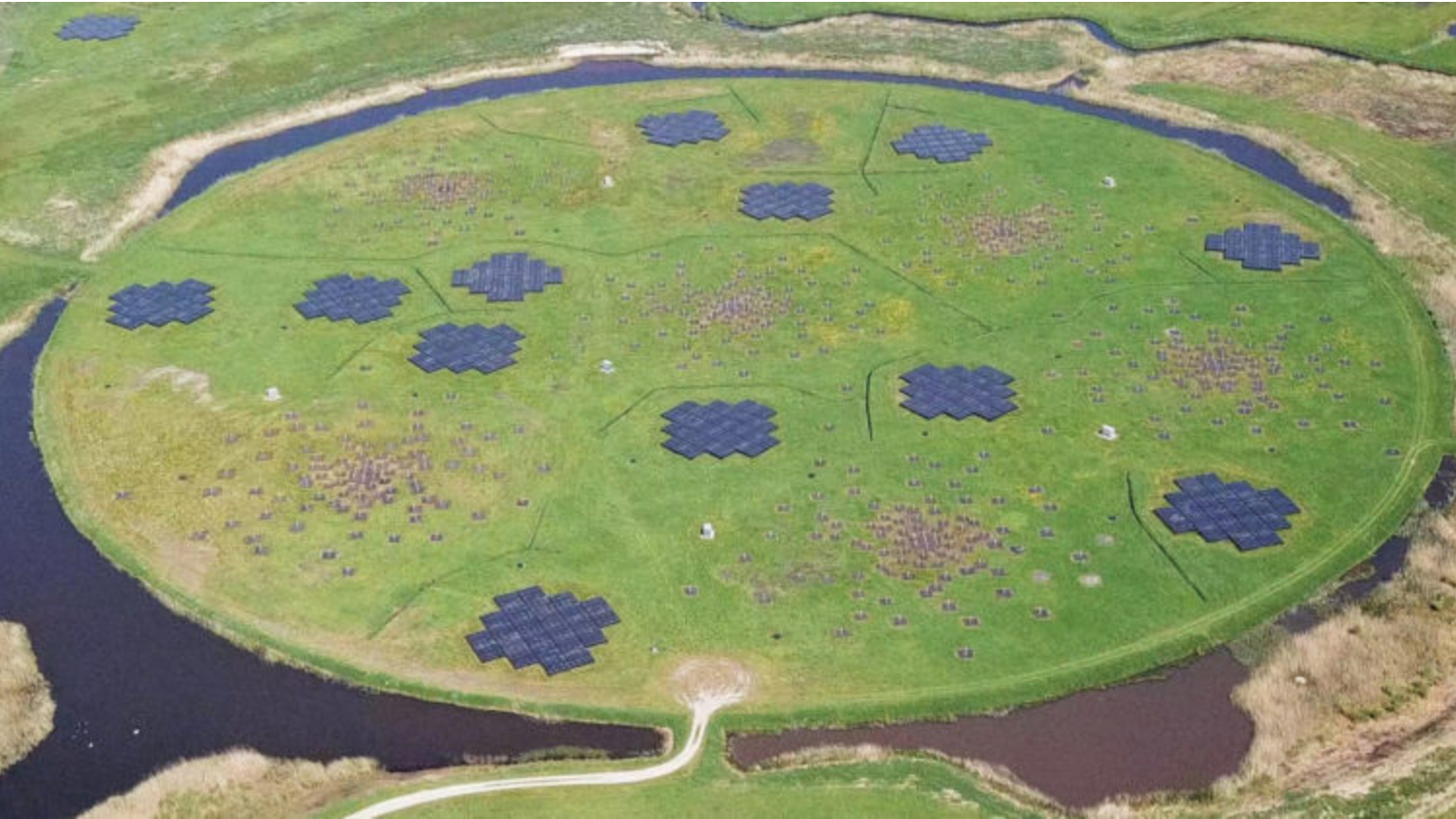 An aerial view of a circular grassy field with many telescope arrays in it