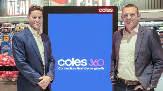 Coles 360 representatives stand in front of digital signage boards powered by Broadsign.
