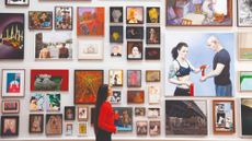 Gallery viewer looking at a collection of artwork on the wall