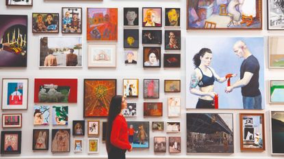 Gallery viewer looking at a collection of artwork on the wall