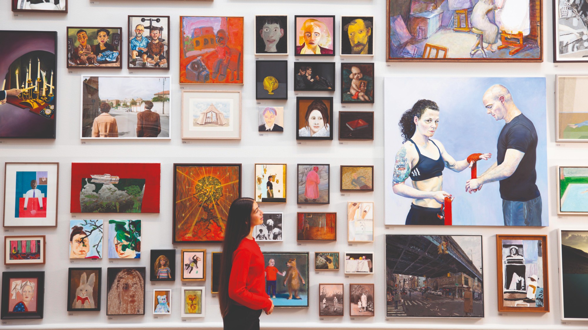 Gallery viewer looking at a collection of artwork on the wall