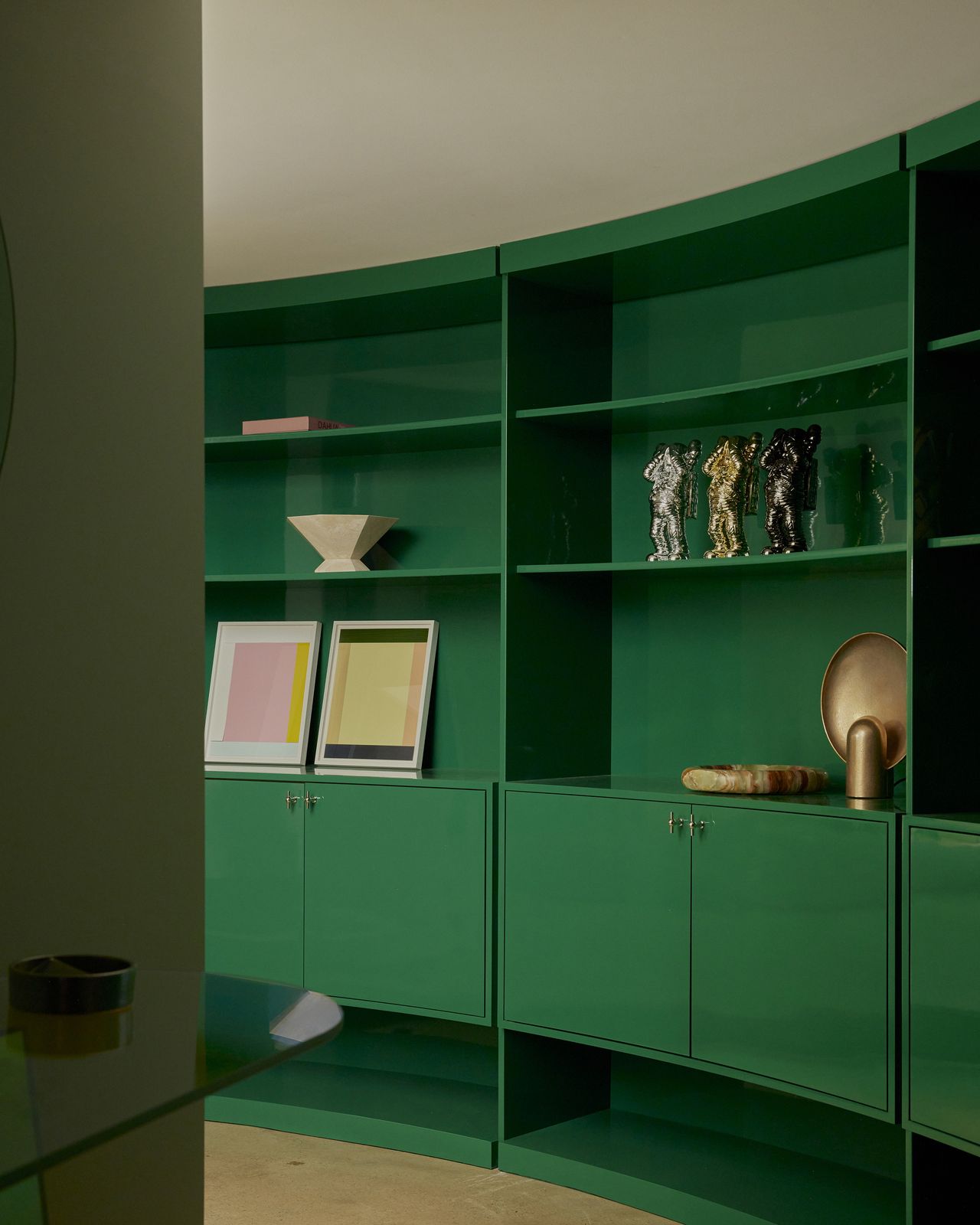 curved green cabinetry with art and sculptures