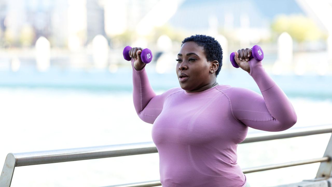 A woman performing a dumbbell shoulder press