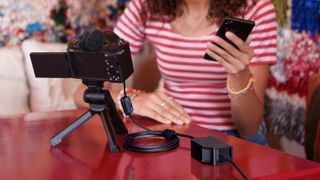 Sony DC-C1 Coupler connected to a camera while a person in a striped shirt films themselves