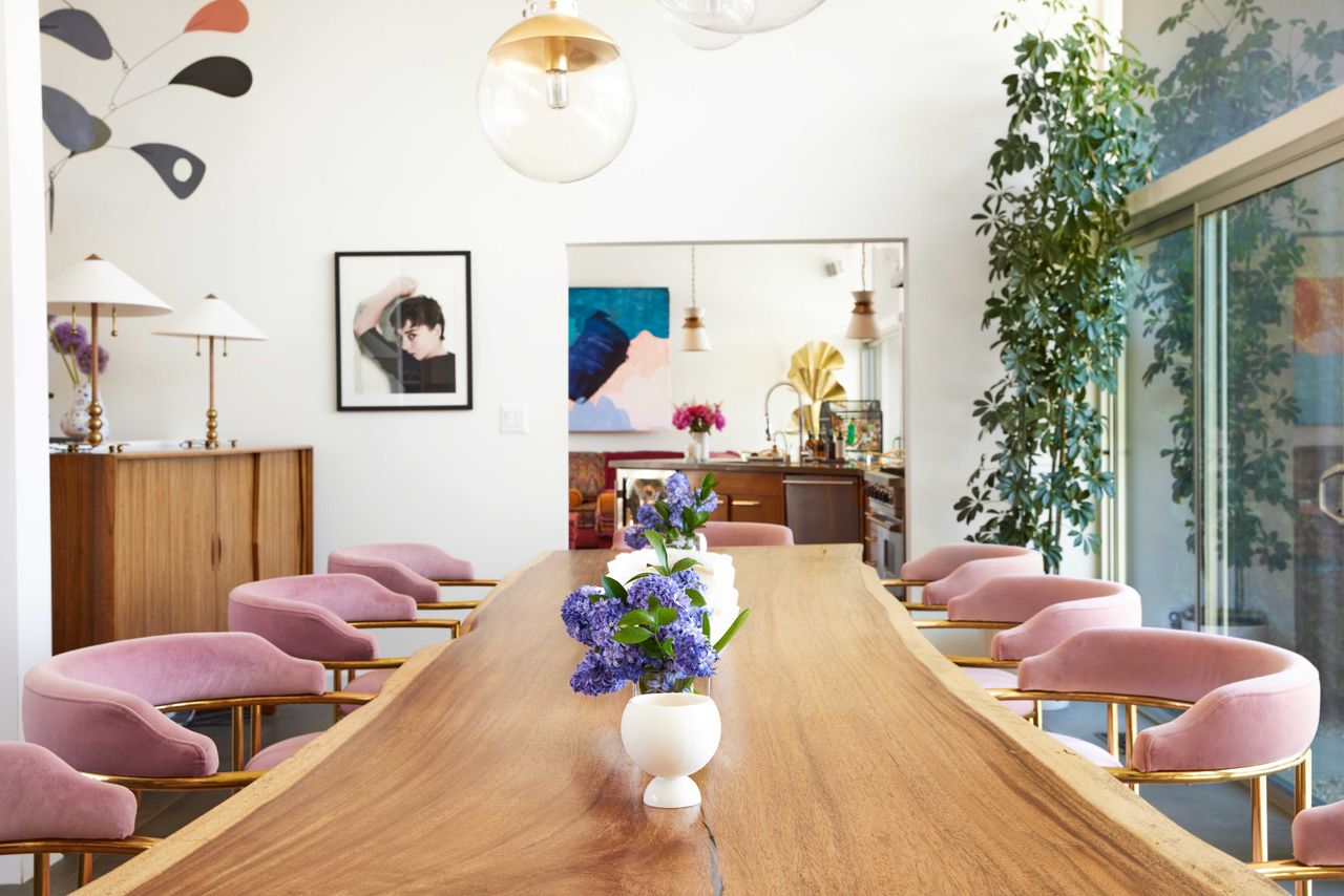 a wood dining table with pink velvet chairs