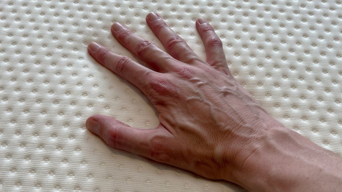 A hand touches the surface of the Emma NextGen Premium mattress
