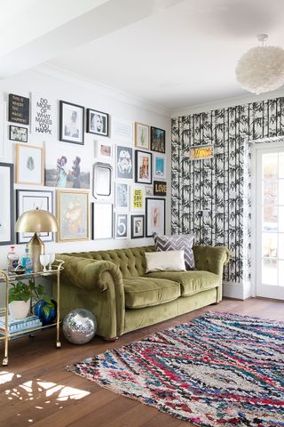 A modern living room with lime green velvet sofa in front of a gallery wall; adjacent to palm print wallpaper wall decor