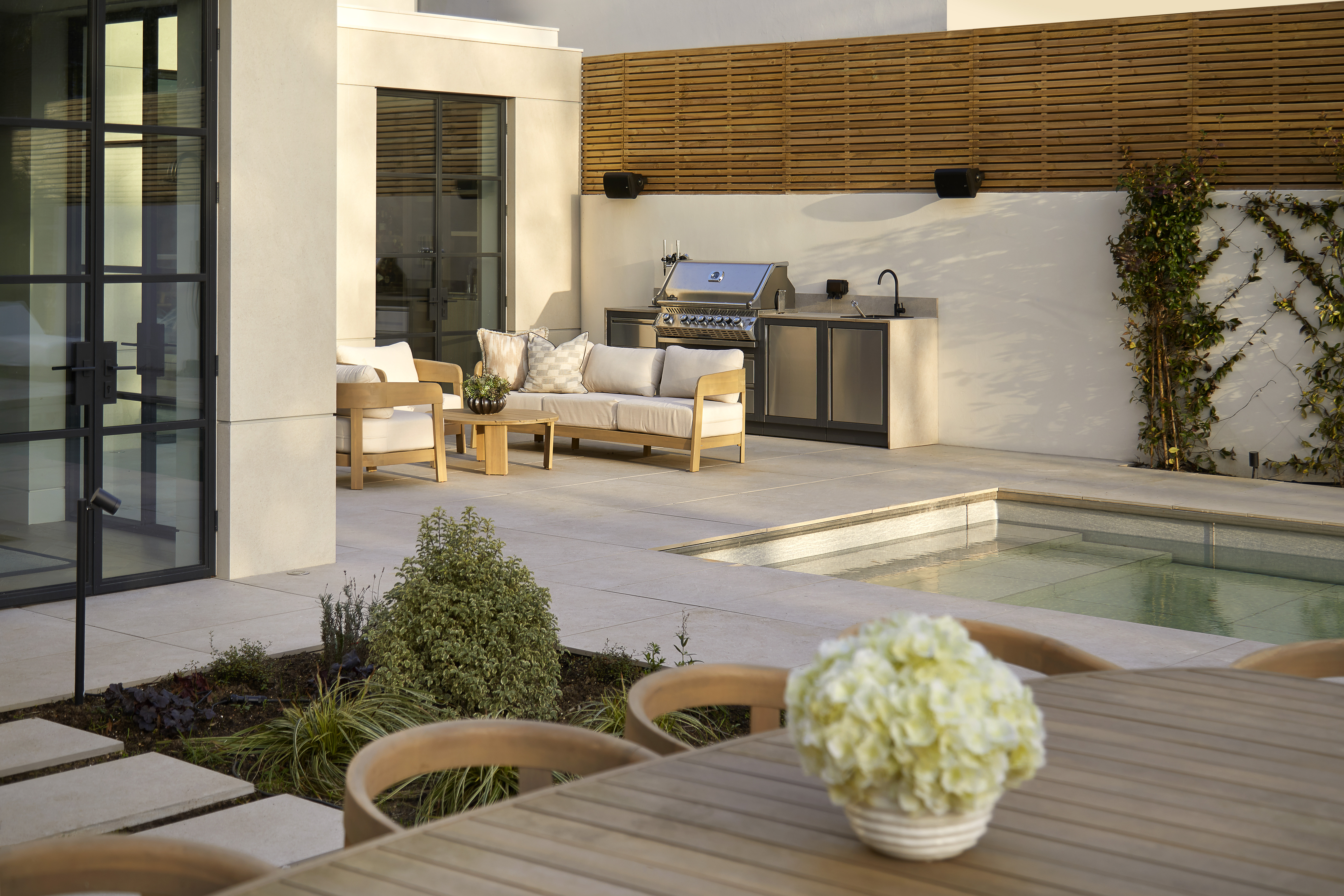 beautiful garden with an outdoor kitchen, dining area, lounge, and a retractable, sinking swimming pool