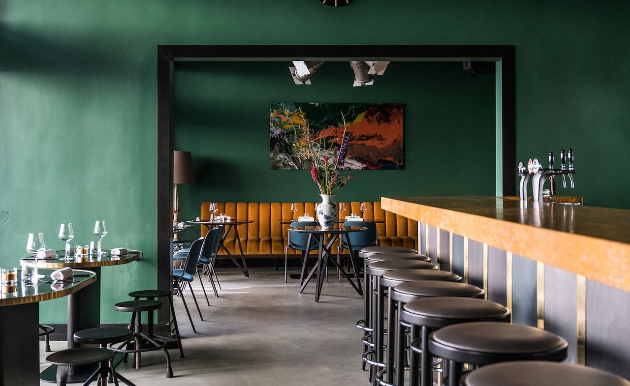 Restaurant interior with green walls &amp; dark furnishings