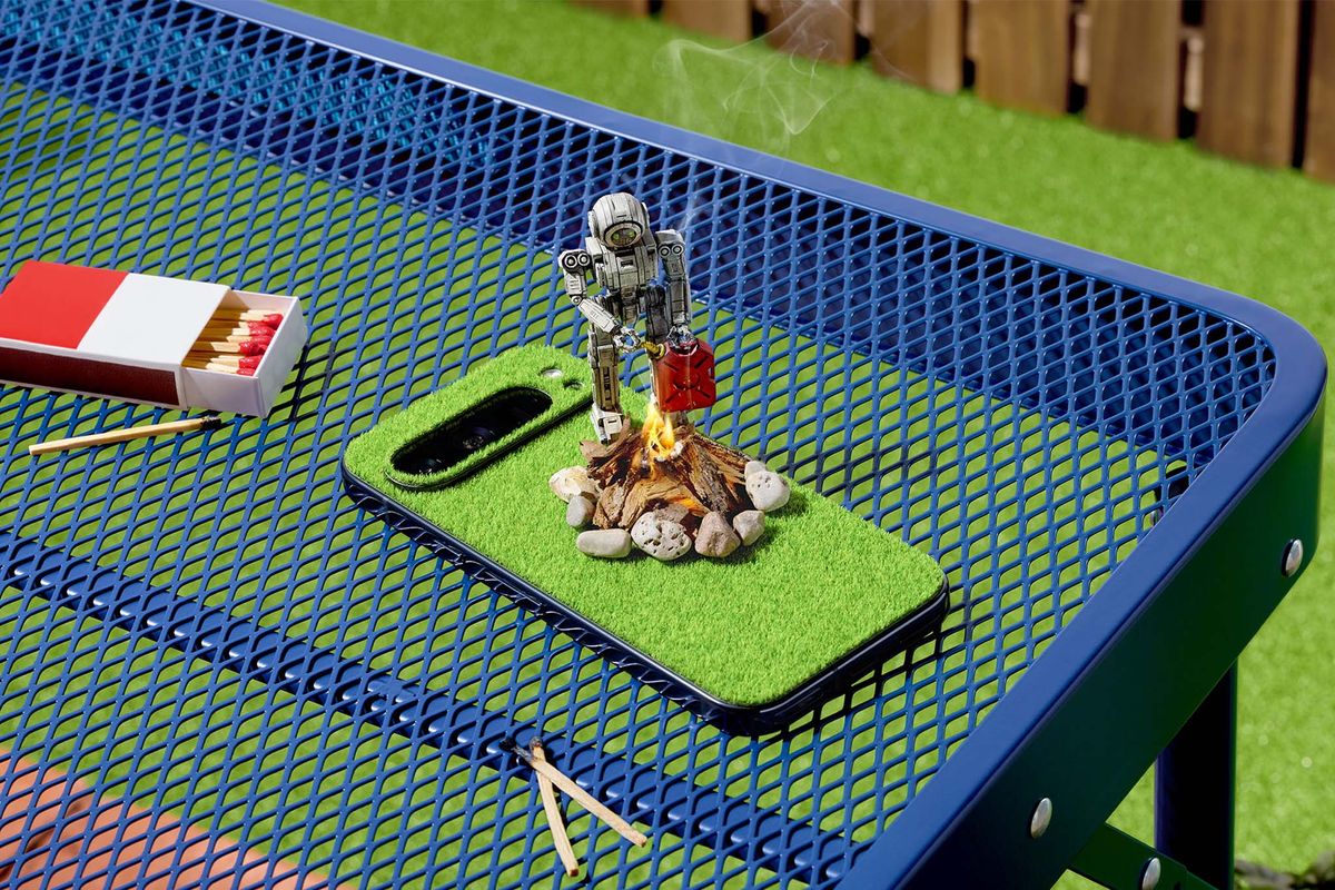 dBrand Touch Grass skin on a Pixel Phone. The phone is outside on a blue table.