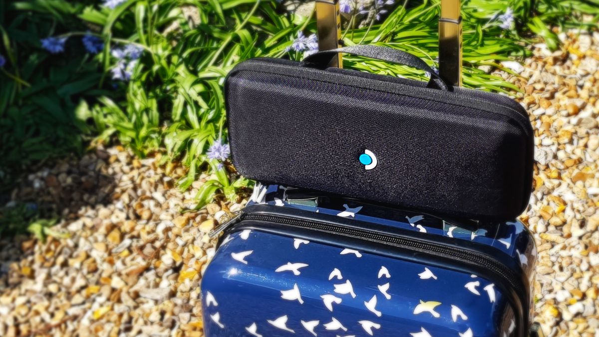 The Steam Deck attached to a suitcase against some bluebells and gravel.