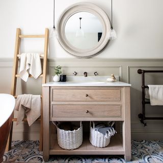 Light wooden bathroom sink cabinets, hanging round mirror and pendant lights