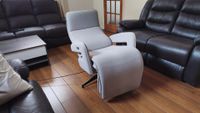 Side view of the recliner fully reclined into its flat position, with its black swivel base visible on the wooden floor.