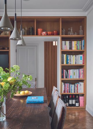 Dark wood dining table with archway surrounded by bookshelves in the background