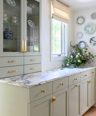 Small kitchen with soft green cabinets, marble worktop and brass hardware