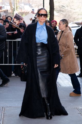 jennifer lopez wearing blue button down shirt, leather skirt, and black coat