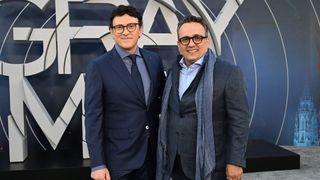 The Russo brothers smile as they stand in front of The Gray Man logo at a premiere for their Netflix film