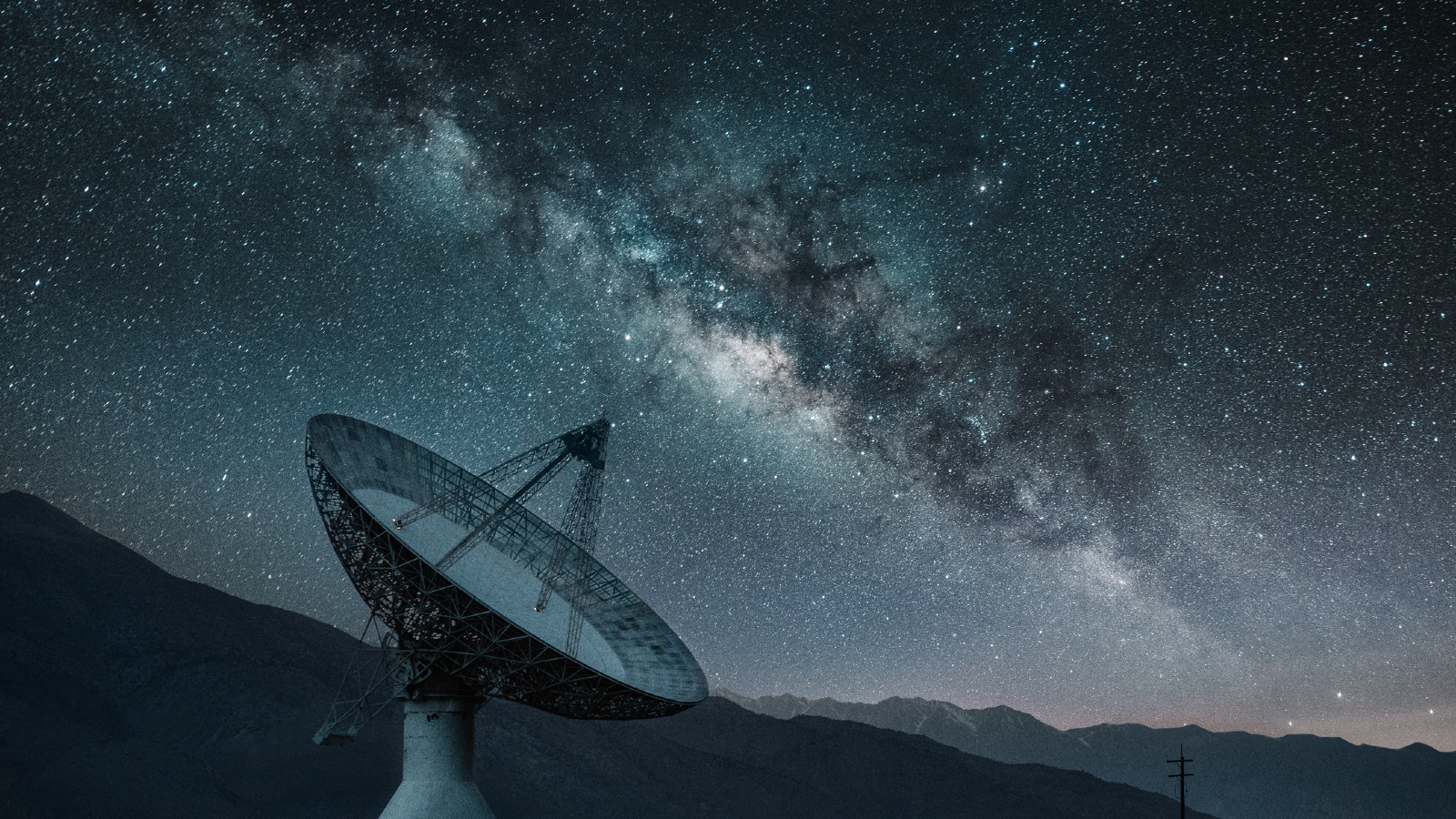 Um radiotelescópio em frente a um céu noturno estrelado