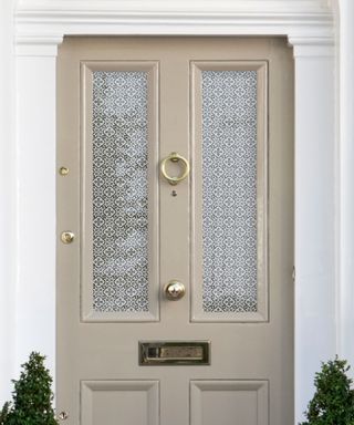 Front door furniture including brass knob and knocker alongside frosted glass windows