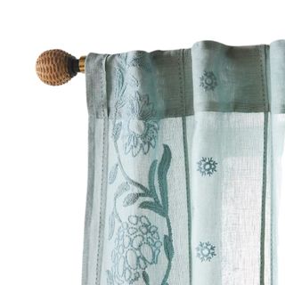 A blue curtain with floral embroidery on a pole