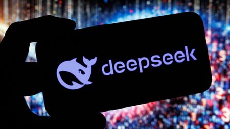 A person holds up a phone with the DeepSeek logo on the screen