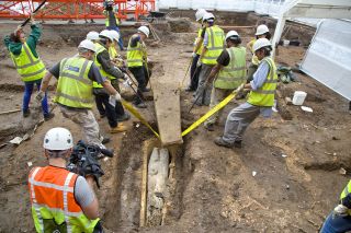 A team of eight lifts the heavy lid of the stone coffin in Leicester.