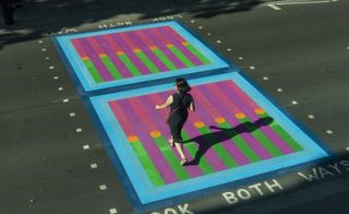 Woman walking over colourful pedestrian crossing on Tottenham Court Road, London