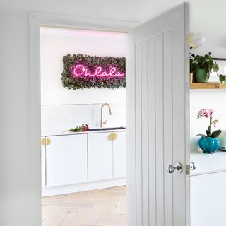 white kitchen with utility room with pink neon sign