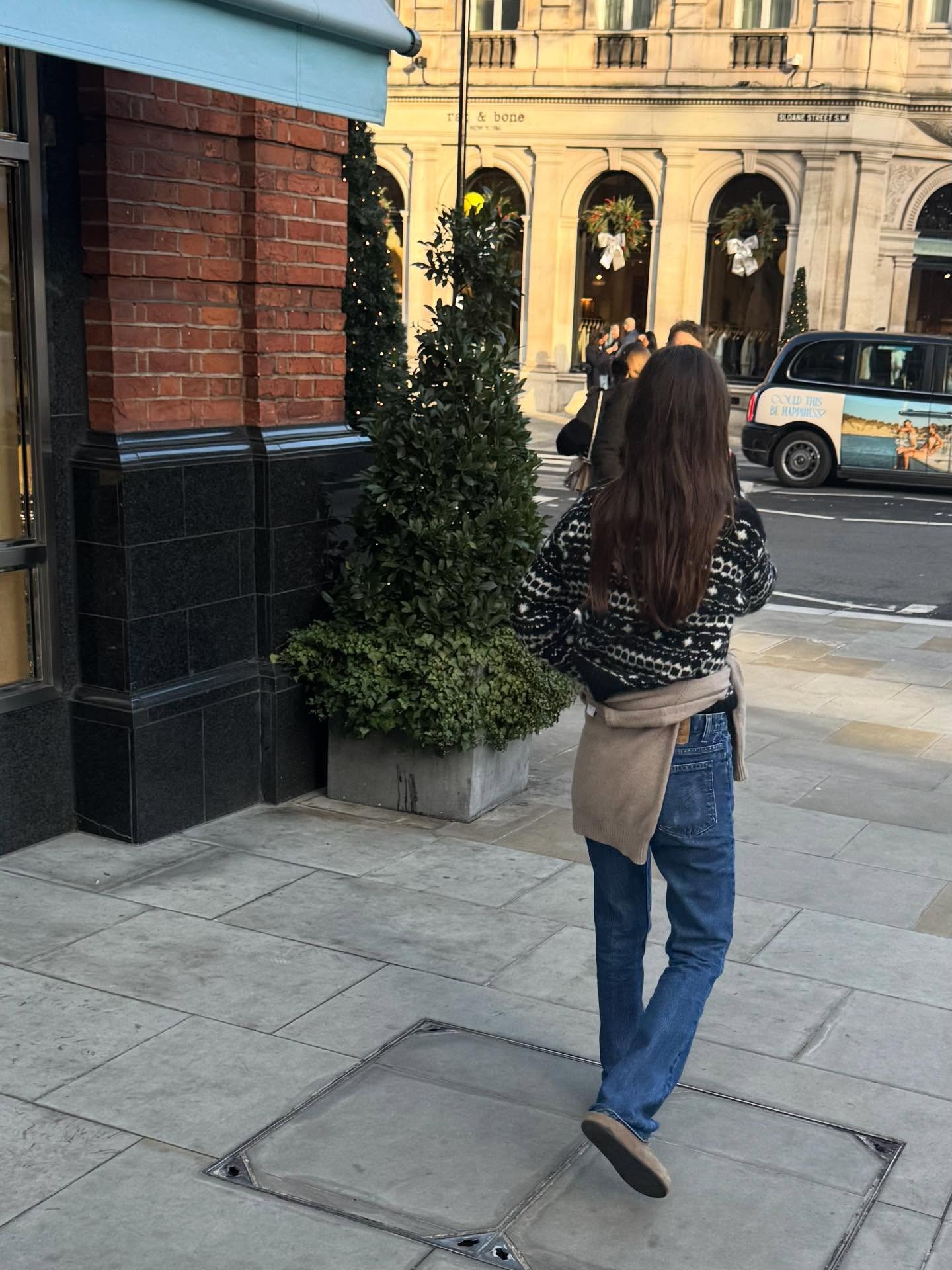 @lauravidrequin wearing a black fair isle sweater with jeans.